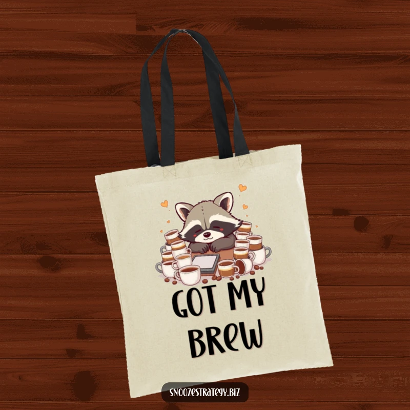 Funny raccoon tote bag, slumped over a desk with numerous coffee cups, expressing a humorous need for caffeine.